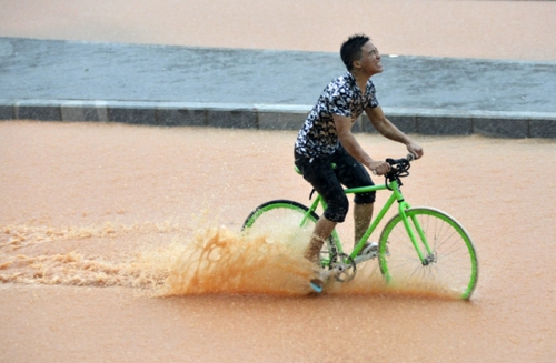 5月11日，一名行人在深圳街頭冒雨騎行。