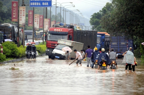 5月18日，國道324線廣西興業(yè)縣石南鎮(zhèn)黑石嶺路段被洪水淹沒，一名群眾手持木棍為摩托車探路。