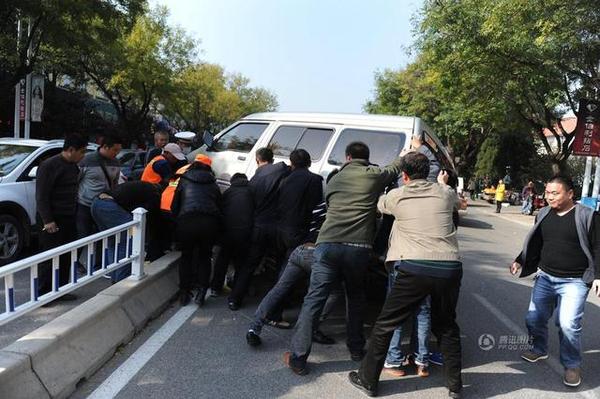 此時周圍路過的市民和附近商販紛紛趕來，十幾人用力抬起面包車，將老人救出。