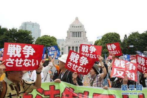 2015年7月14日，日本民眾在國會外集會，手舉標語牌，高喊口號示威，抗議新安保法