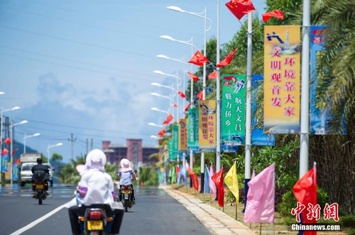 6月24日，海南省文昌市龍樓鎮(zhèn)街道兩側(cè)五星紅旗迎風(fēng)飄揚(yáng)，火箭“首發(fā)”宣傳廣告隨處可見。長征七號(hào)運(yùn)載火箭發(fā)射日期臨近，中國首個(gè)濱海航天發(fā)射中心——文昌航天發(fā)射場所在地海南省文昌市龍樓鎮(zhèn)將迎來“首發(fā)”，中國的“卡納維拉爾角”正揭開神秘面紗。中新社記者 駱云飛 攝