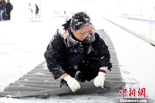 圖為鐵路工作人員在站臺上鋪設防滑墊。　秦姝　攝