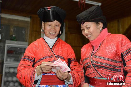 1月27日，廣西龍勝各族自治縣龍脊鎮(zhèn)大寨村的瑤嫂正在清點(diǎn)分到的梯田維護(hù)費(fèi)。1月27日至1月28日，廣西龍勝各族自治縣龍脊鎮(zhèn)大寨村村委會(huì)將110多萬(wàn)元的“紅利”分發(fā)到200多戶的群眾手中。龍脊鎮(zhèn)大寨村從2003年開寨接待游客以來(lái)，該縣通過旅游扶貧方式引導(dǎo)該村群眾以梯田入股方式與當(dāng)?shù)氐凝埣孤糜喂韭?lián)營(yíng)，旅游公司則將門票收入按一定的比例為當(dāng)?shù)氐拇迕癜l(fā)放梯田維護(hù)費(fèi)。目前，大寨村的游客多了，大部分村民開設(shè)了農(nóng)家旅館，和販賣瑤族工藝品等，使其成為當(dāng)?shù)厝罕娫鍪罩赂坏闹饕馈?lt;a target='_blank' href='http://www.chinanews.com/'>中新社</a>發(fā) 韋吉陽(yáng) 攝