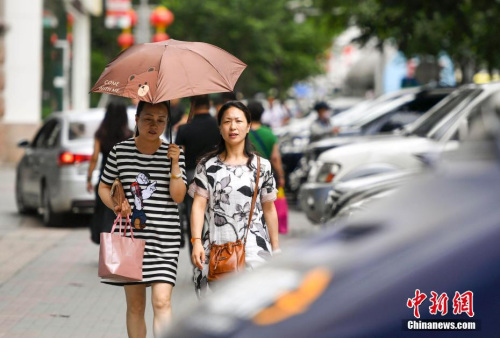 新疆烏魯木齊市街頭，民眾打傘抵擋高溫天氣。