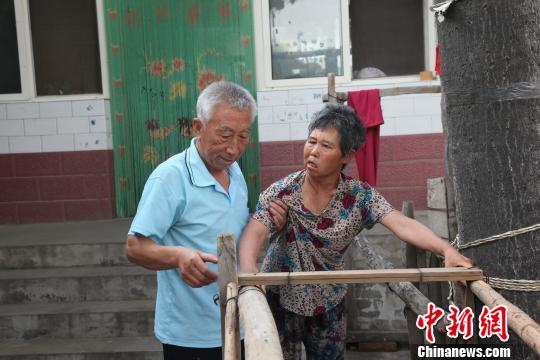 為讓妻子慢慢學會走路，李文生每天扶著妻子一遍一遍練習走路。　李院紅 攝