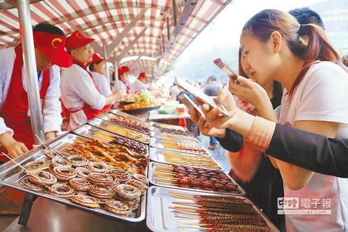 北京一“蟲子宴”攤位，擺滿串蛇、蜈蚣、螞蚱、蜘蛛等，不少食客拿出手機拍照。（臺灣中時電子報）