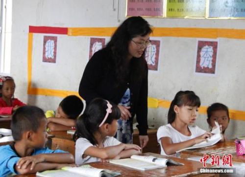 9月22日，在偏遠山區的廣西柳江縣穿山鎮六廟小學，幾間瓦房教室、宿舍，操場上3張乒乓球臺就是學生和老師的一切。48歲的韋鳳玲在給學生們上課，“下雨時，人在上課雨從頭頂落”，韋鳳玲這樣形容學校環境。2014年從老撾完成兩年支教任務的柳江縣第二中學教師韋鳳玲，又到該縣土博鎮、穿山鎮村級小學支教，被稱為支教“專業戶”。朱柳融 攝