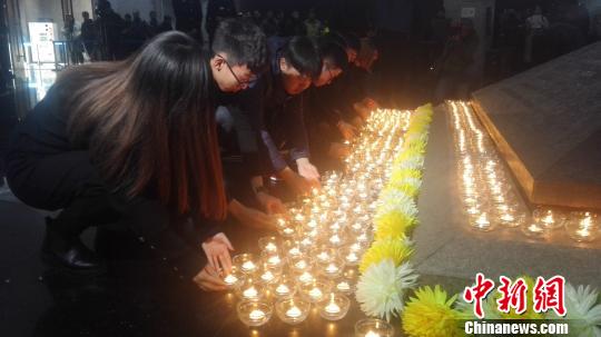 12月13日，沈陽“九一八”歷史博物館在國家公祭日舉行悼念儀式。圖為民眾向寓意民族英烈浩氣長存的金字塔型臥碑敬獻(xiàn)燭火。　朱明宇 攝