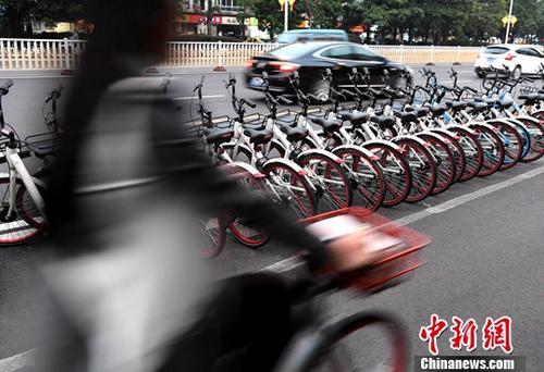 資料圖：路人騎著共享單車經過“車堆”。<a target='_blank' href='http://www.chinanews.com/'>中新社</a>記者 張斌 攝