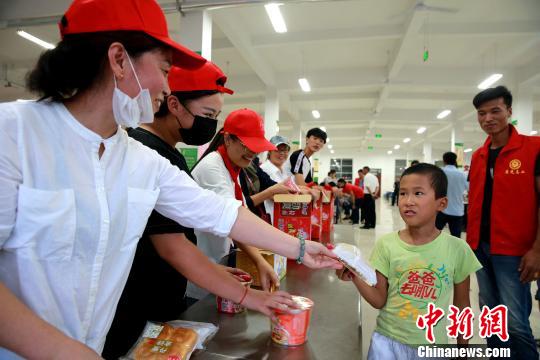 8月24日，志愿者在濰坊壽光市營里鎮(zhèn)第二初級中學(xué)安置點(diǎn)為災(zāi)民發(fā)放救援物資。　梁犇 攝