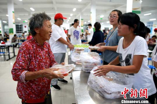 8月24日，志愿者在濰坊壽光市營里鎮(zhèn)第二初級中學(xué)安置點(diǎn)為災(zāi)民發(fā)放救援物資。　梁犇 攝