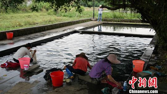 幾名婦女在“雅蔡冷泉”旁一邊聊天一邊洗著衣物。　符宇群 攝