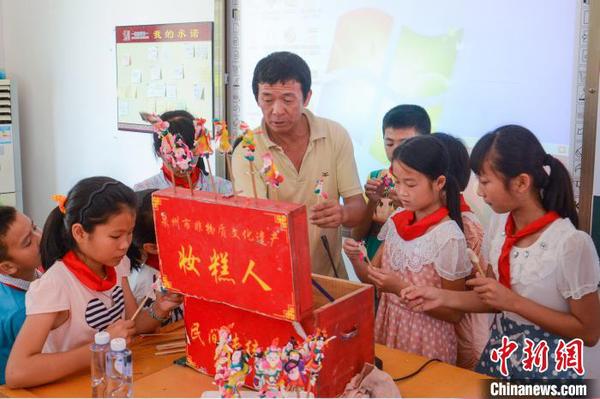張明鐵到學校為孩子們教授“妝糕人”制作技藝。　張藝欣 攝