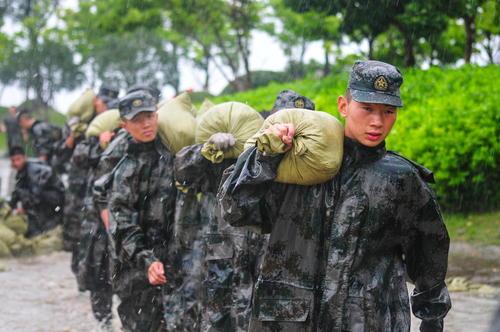 圖為在安徽合肥巢湖任務(wù)區(qū)官兵在暴雨中扛運(yùn)沙袋，加固堤壩。（王文洲 攝）